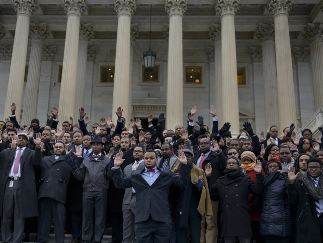 African-American Congressional staff and others hold their hands up during a walk-out outside the House of Representatives on Capitol Hill on December 11, 2014 in Washington, DC. Congressional staff members and others stood outside the Capitol to protest the Eric Garner and Mike Brown grand jury decisions which did not bring charges against police. AFP PHOTO/BRENDAN SMIALOWSKI (Photo credit should read BRENDAN SMIALOWSKI/AFP/Getty Images)