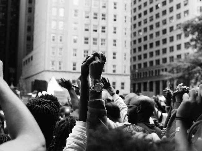 Picture of people holding hands up in the air at a protest